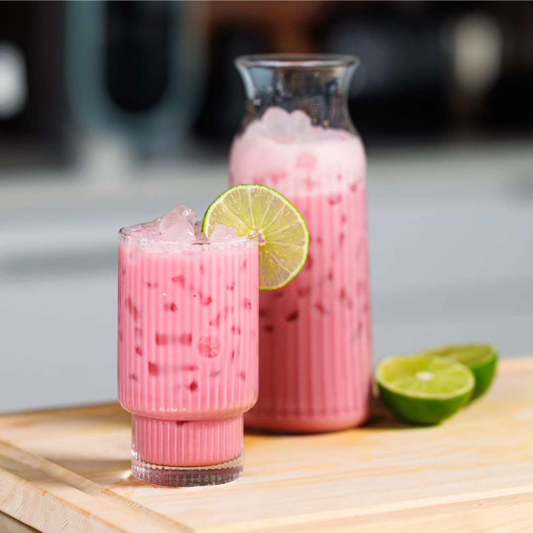 Glass of bright pink icy beverage with a lime wheel