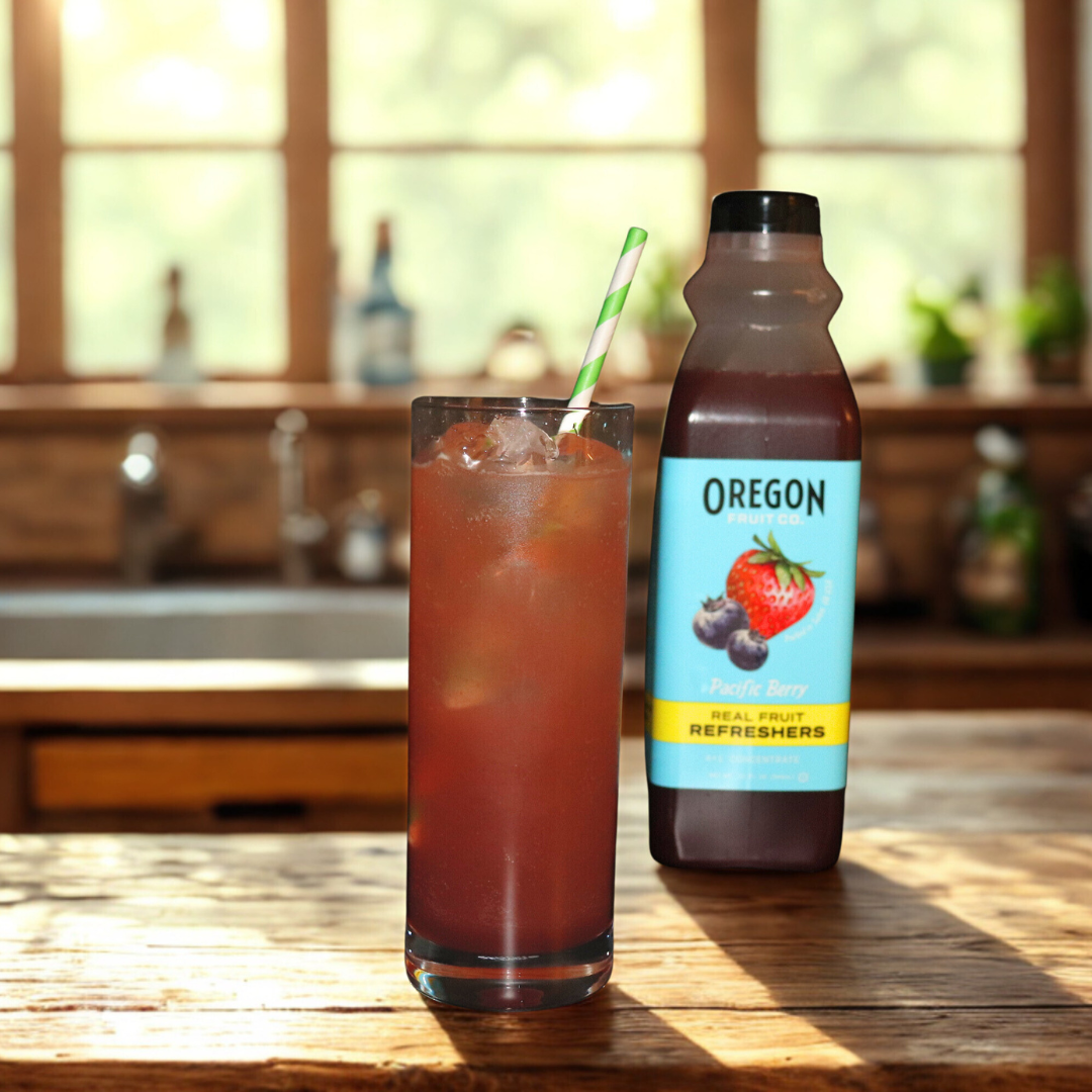 Glass on wooden table next to bottle of Pacific Berry Refresher