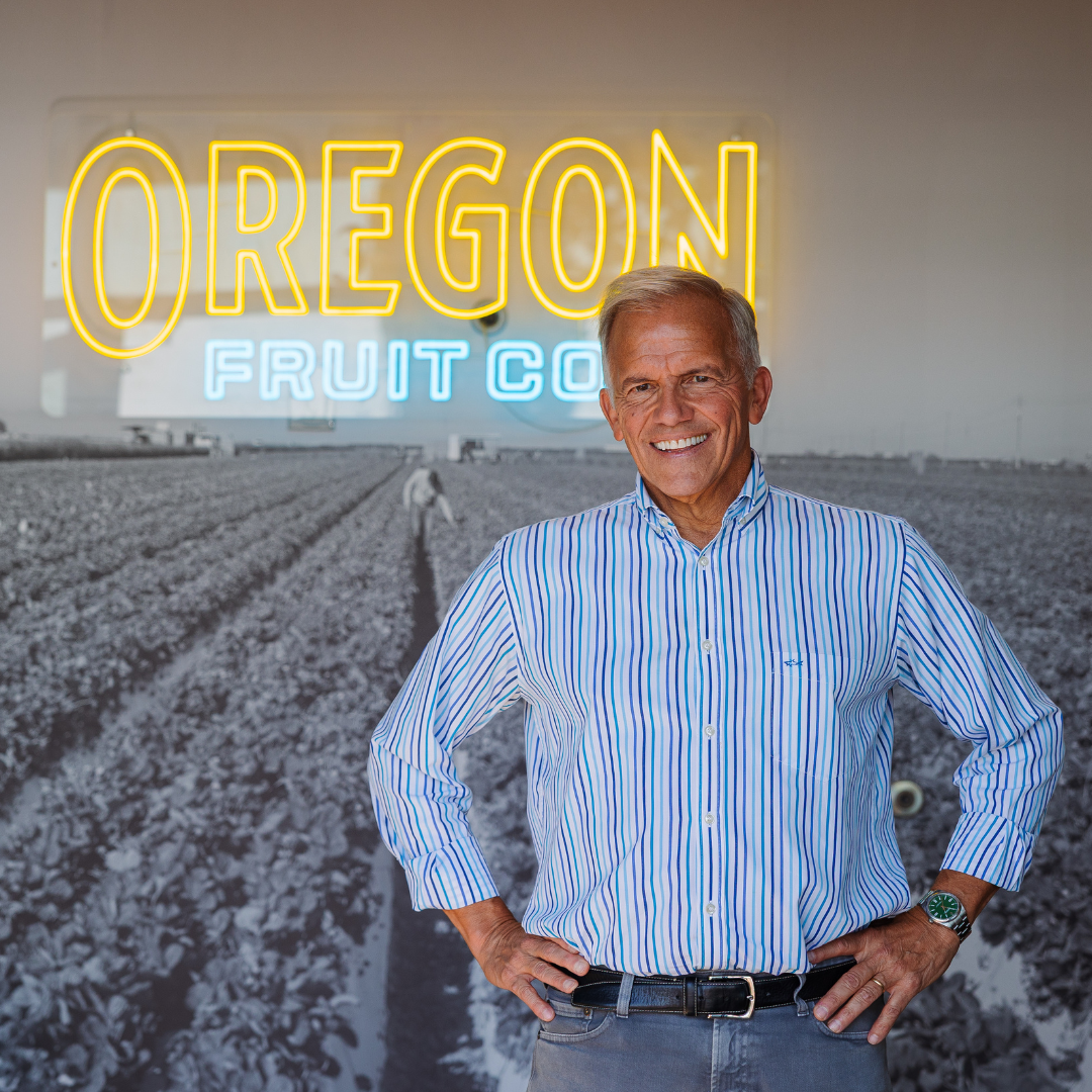 man in a blue button down shirt stands in front of a neon sign