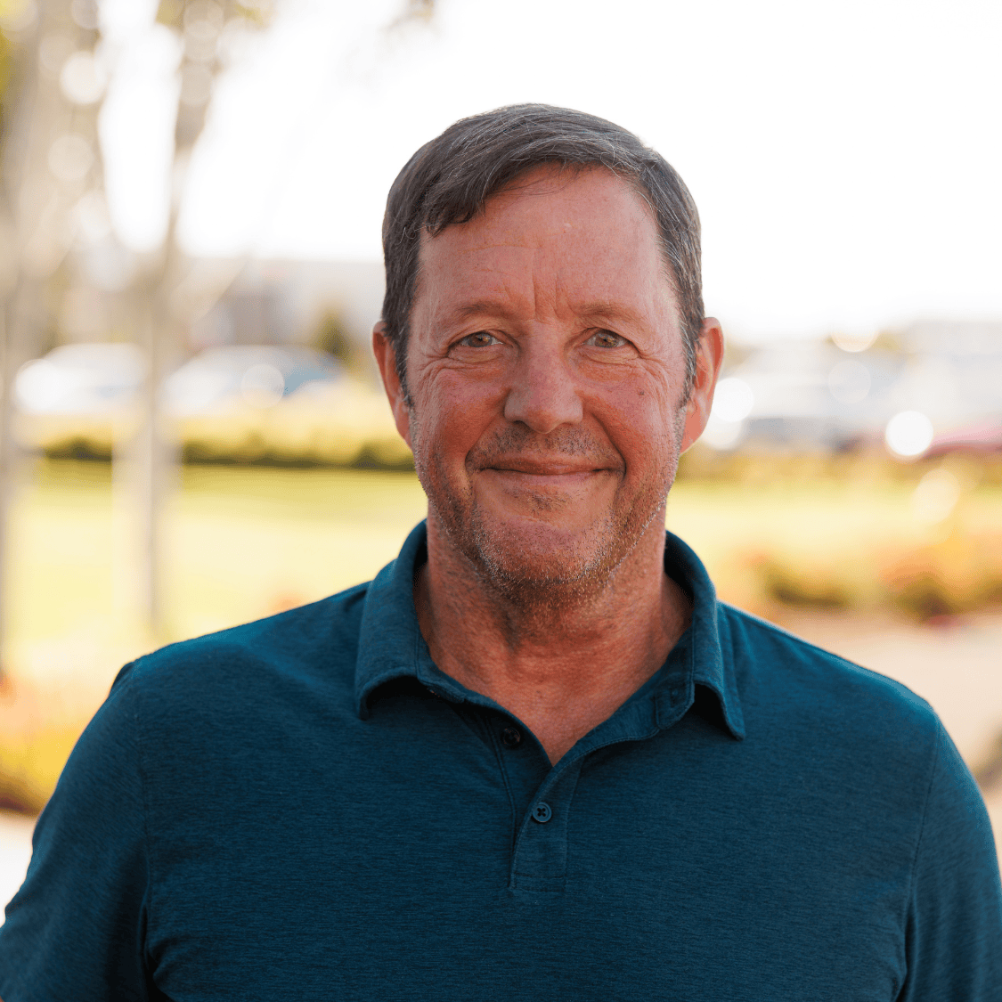 headshot of a man in a teal polo shirt