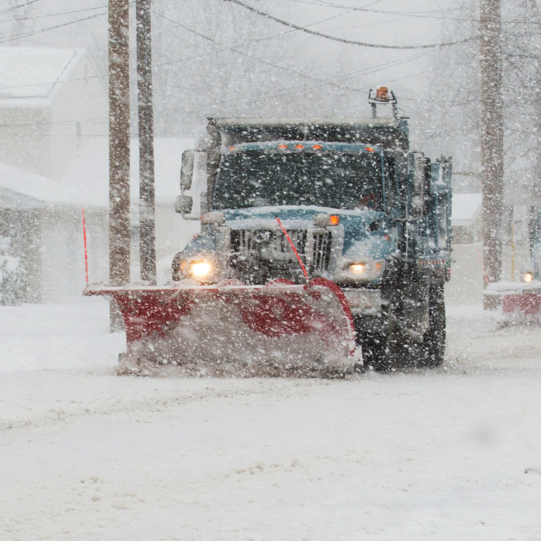 a snow plow clears a road in a snowstorm