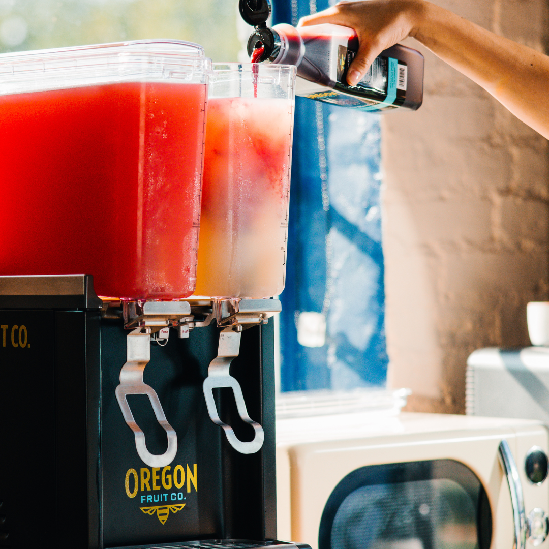 Fruit puree being poured from bottle into a beverage dispenser