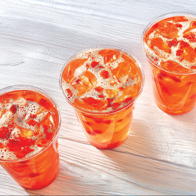 three colorful drinks with ice in clear cups