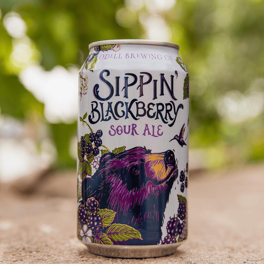 A purple bear surrounded by blackberries sits on the label for a can of Sippin' Blackberry Sour Ale