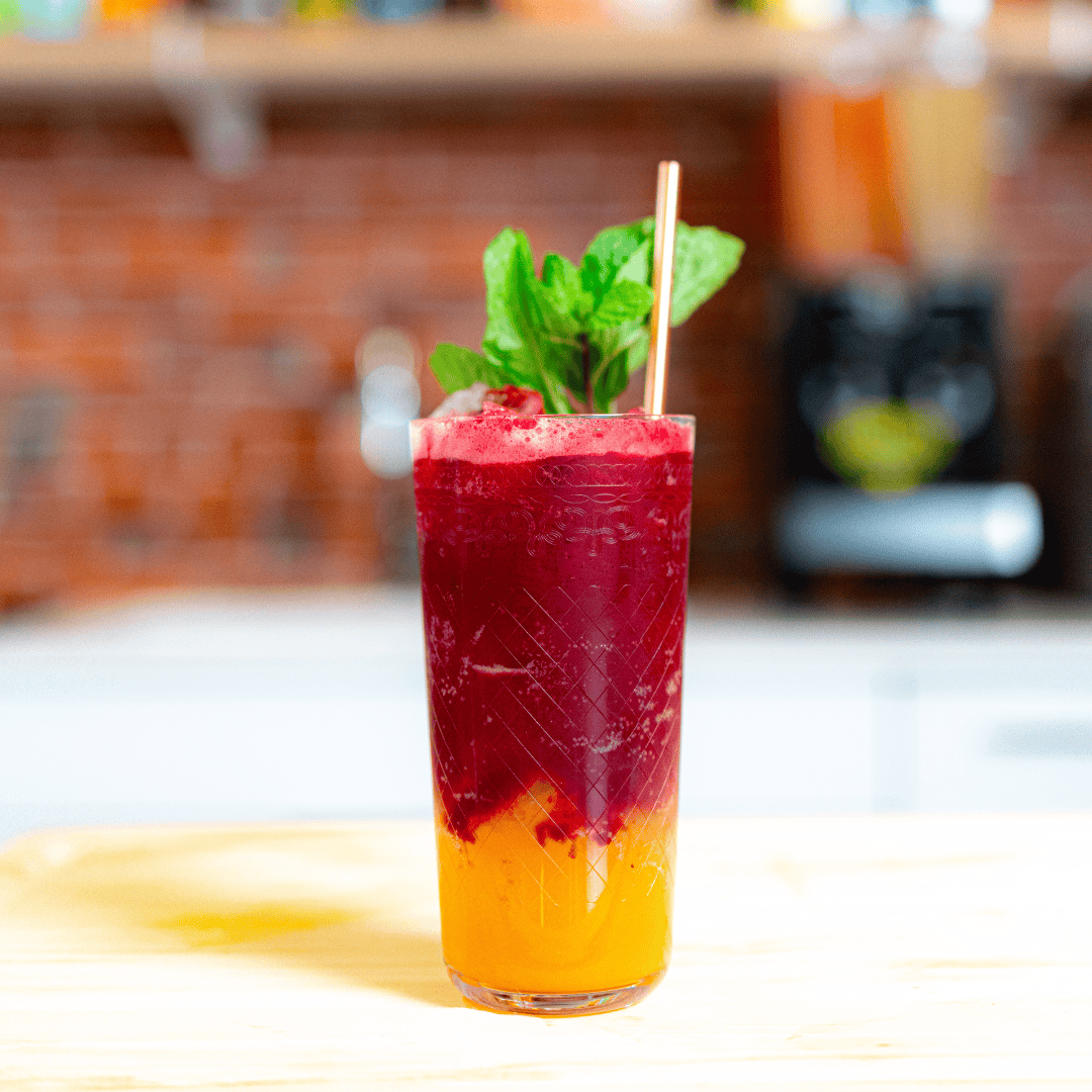layered red over orange passion fruit mocktail in a glass