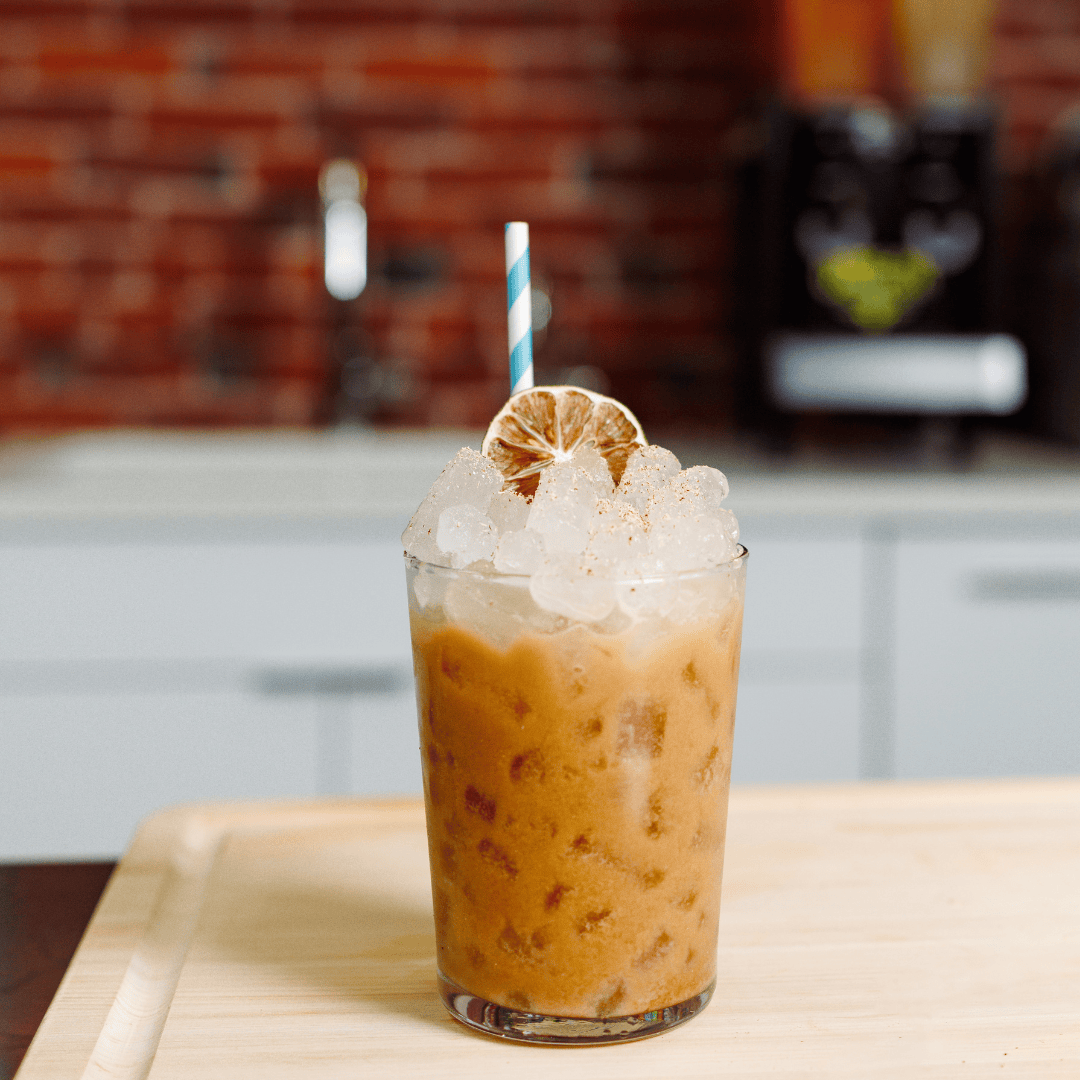 a glass of iced coffee topped with a dried lime wedge
