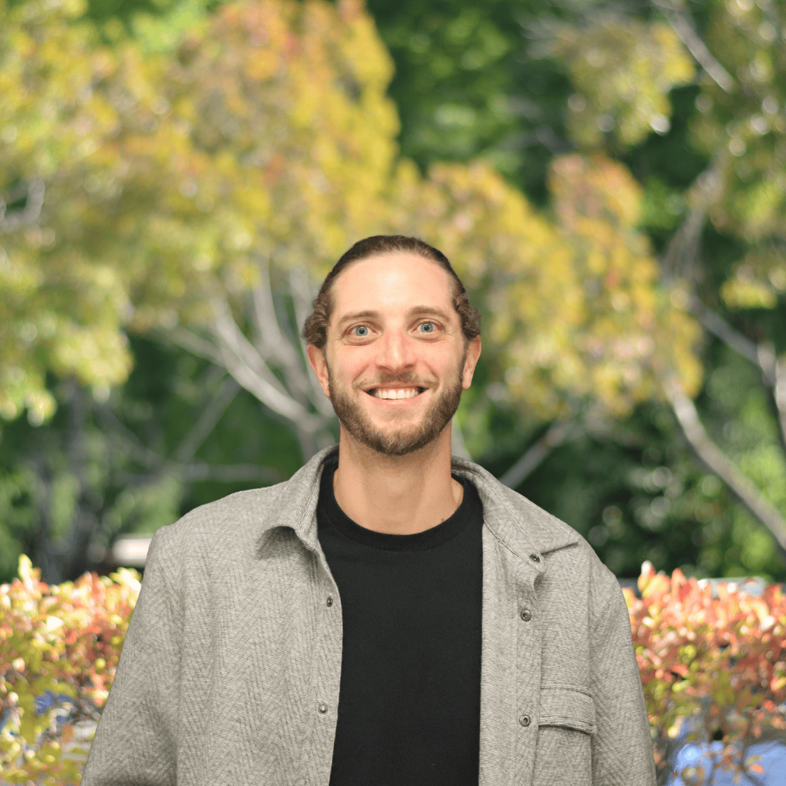 headshot of a man in a black t-shirt under a grey button up shirt