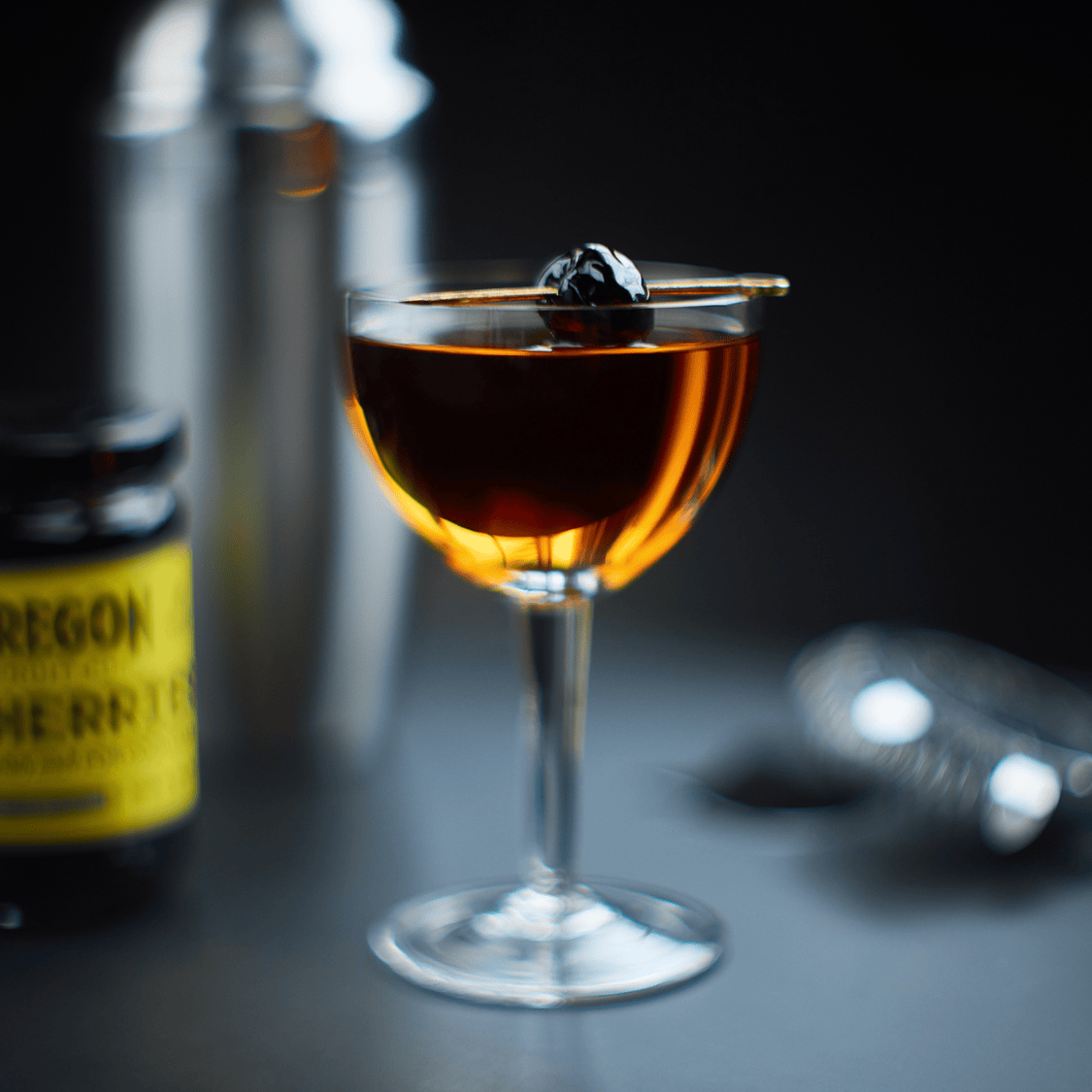image of a perfect manhattan cocktail in front of a jar of Oregon Fruit cocktail cherries
