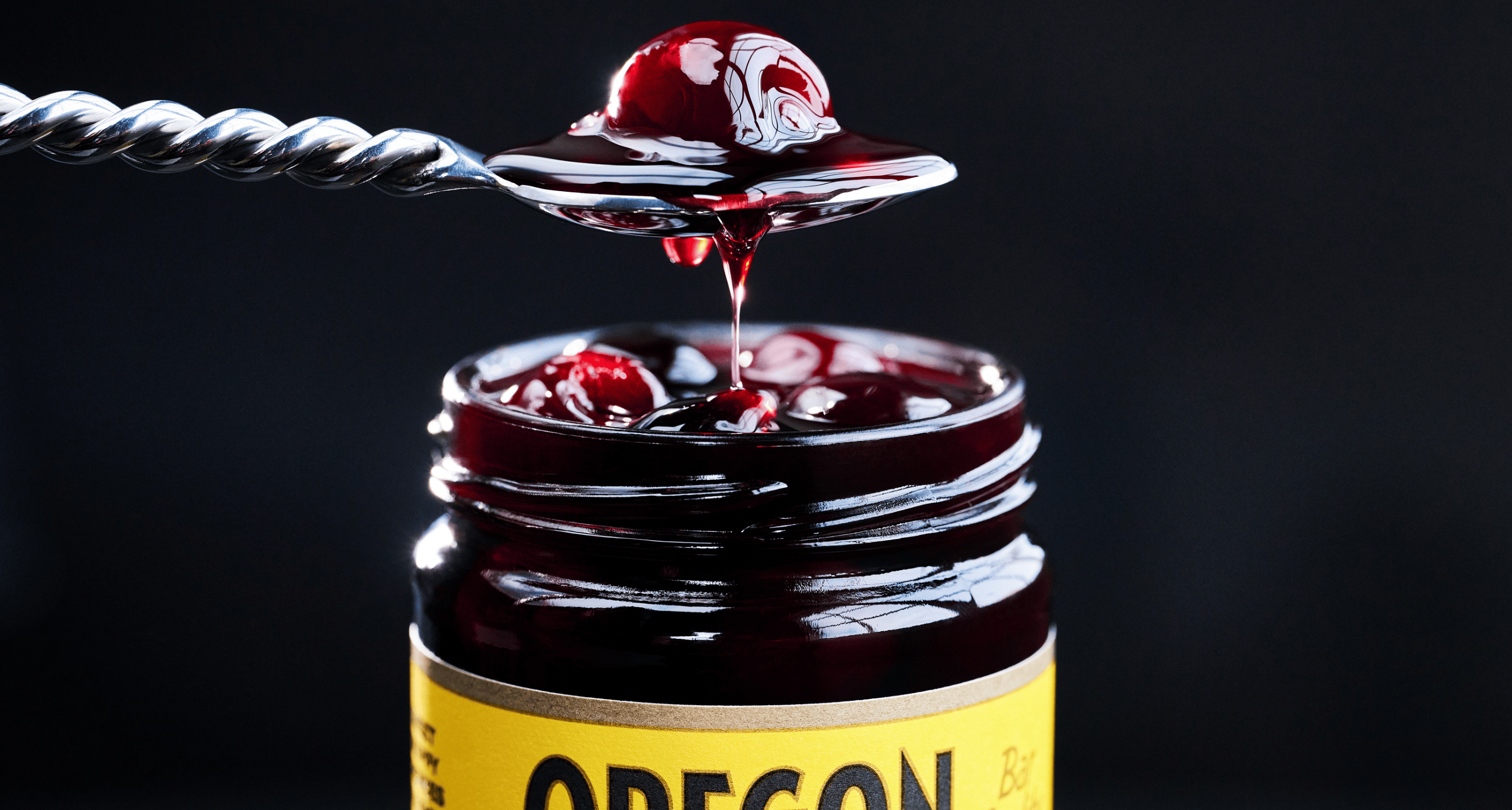 Spoon reaching into a jar of Oregon Fruit cocktail cherries 